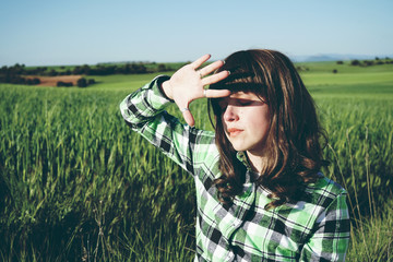 Mujer joven y relajada en un campo verde de cereales 