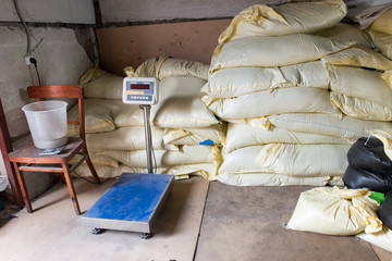 Sacks with mixed fodder for poultry and scales in stock. Fodder for chickens, ducks, geese, quail.