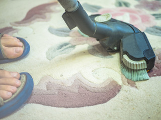 close up vacuum cleaner with foot on the carpet at home