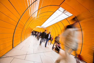 People rushing through a subway corridor (motion blur technique is used to convey movement)