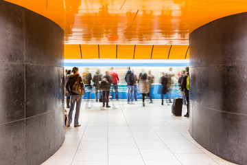 People rushing through a subway corridor (motion blur technique is used to convey movement)