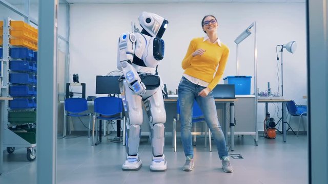 Young woman is dancing with a robot who spanks her playfully after whereafter she leaves