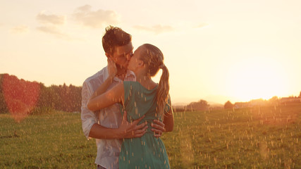 Fototapeta na wymiar CLOSE UP: Cheerful young couple kisses in the rain during romantic outdoor date.