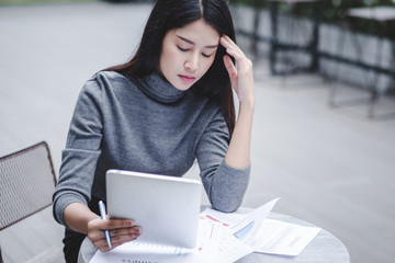 Business woman holding a tablet computer stressed because of falling stock