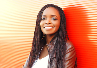 Fashion smiling african woman in city over red background