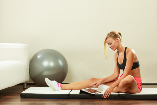 Fit woman sitting on floor with tablet pc