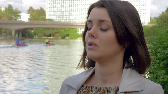 Sad woman crying in front of lake in city unhappy medium shot