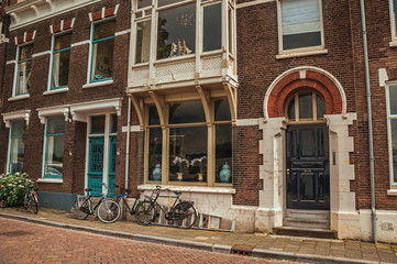 Facade of elegant brick building with door in an unusual design and bicycles on the street in Dordrecht. Important and historic port city bordered by rivers.  Southern Netherlands.
