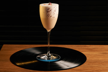 Classical Lucy cocktail on vinyl tray background. Cocktail with Gin, Yogurt, liqueur, Lychee puree, Cardamom syrup, egg white, Lemon juice. Sweet cocktail with spicy taste, close-up
