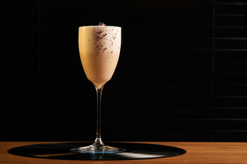 Classical Lucy cocktail on vinyl tray background. Cocktail with Gin, Yogurt, liqueur, Lychee puree, Cardamom syrup, egg white, Lemon juice. Sweet cocktail with spicy taste, close-up