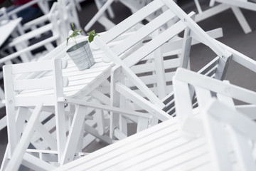 Heaps of inverted white plastic chairs on tables in closed restaurant on terrace close-up. Beautiful graphic chaos, interesting background