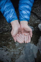 A man's hands cupping cold water. 