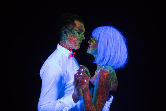 Neon photography bright colorful on a dark background in the rays of ultraviolet steam in love guy and girl bride with groom at a wedding first wedding dance UV