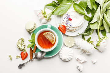 tea with cakes, fruits and flowers on a white table