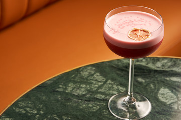 Classical Katana cocktail on table, close-up. Freshly cocktail with Rum, Passionfruit pure, Egg white, Sumax syrup, Ginger infuse. Sour-sweet, light, spicy alcoholic drink