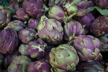 Fototapeta na wymiar Young fresh, green and purple Artichokes for Sale on a Fresh Market