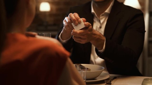 Man giving an engagement ring to his girlfriend at the restaurant