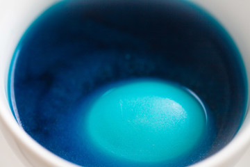 The process of coloring Easter eggs. Eggs are immersed in liquid with paint.