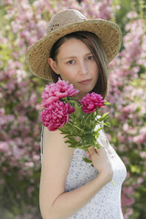 Portrait of young woman with bouquet of flowers in the garden