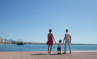 Happy family on the beach. People look at future on summer vacation. Father, mother and child against blue sea and sky background. Holiday travel concept.