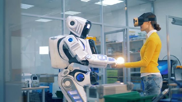 Human-like android is putting its hands on top of lady's palms