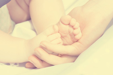 Baby feet in mother hands. Tiny newborn baby feet, concept of happy family. Instagram