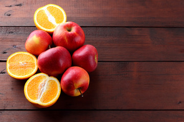 Fototapeta na wymiar Fruits of oranges and red apples on a dark brown wooden background, halves of oranges on wooden boards. Citrus fruits and apples for vegetarian breakfast