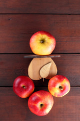 Fruits of oranges and red apples on a dark brown wooden background, halves of oranges on wooden boards. Citrus fruits and apples for vegetarian breakfast
