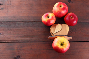 Fruits of oranges and red apples on a dark brown wooden background, halves of oranges on wooden boards. Citrus fruits and apples for vegetarian breakfast