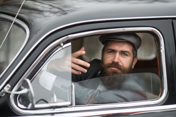 Retro man in retro car showing communicative gesture.