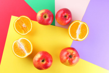 Fruits of oranges and red apples on a multicolored background, halves of oranges and apples on colored paper. Citrus in the style of pop art