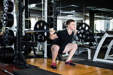 Fototapeta na wymiar Newbie bodybuilder in black sportswear lifting heavy weight in gym