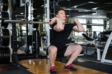Fototapeta na wymiar Bodybuilder in black sportswear lifting heavy weight in the gym