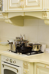 Stove with pots and pans on countertop. Stove with cooking utensils on white wall tile. Kitchen appliance and furniture. Kitchen design in vintage style. Cooking at home concept