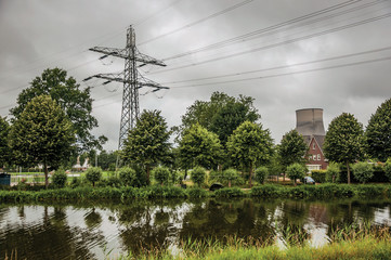 View of canal and gardens with nuclear power plant in background on cloudy day, near the village of Geertruidenberg. A small, friendly place near Aakvlaai Park and Breda. Southern Netherlands.