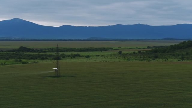 AERIAL VIEW from above of a flying paraglider. Beautiful paraplaner on the background of wild nature: rocky mountains, green meadows and plains 4k