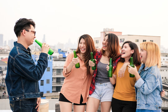 Group of asian friends drinking at rooftop party, casual outdoors celebration