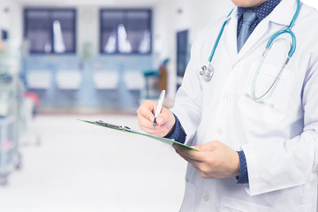 Male Doctor with files and stethoscope on hospital corridor holding clipboard and writing a prescription,Doctors Medical Exam,Healthcare and medical concept,test results, registration,selective focus.