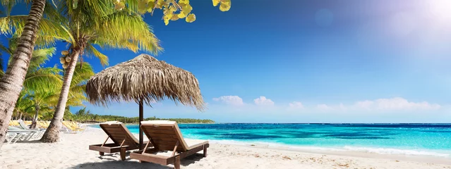 Foto auf Glas Karibik Palm Beach mit Holzstühlen und Strohschirm - Idyllische Insel © Romolo Tavani