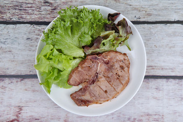 Pork Chop Steak served with mixed vegetable as red oak , green oak and lettuce