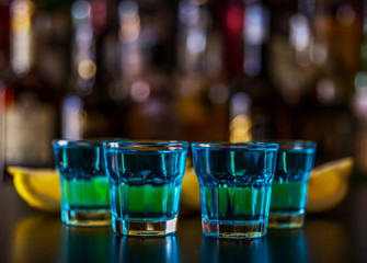 Popular blue drink shot kamikaze on the background of the bar with bottles, a refreshing drink
