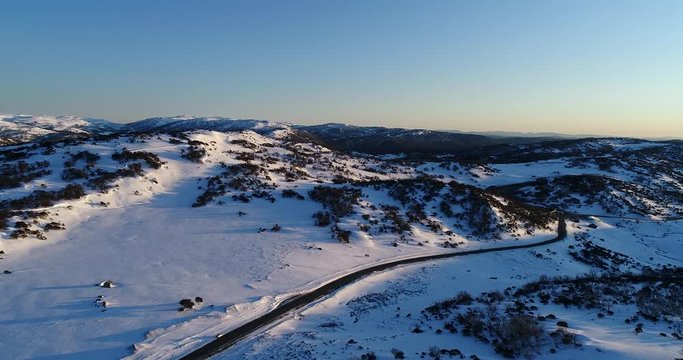 White snow in Perisher valley of Snowy mountains ski resort area of Australia at sunrise with clean slopes and snow fields along the road.
