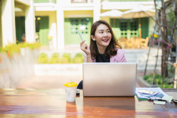 Smiling Businesswoman working in office with documents and holding pen,Happy Asian business woman using laptop sitting on chair at modern home studio.people working mobile devices,contact to costumer