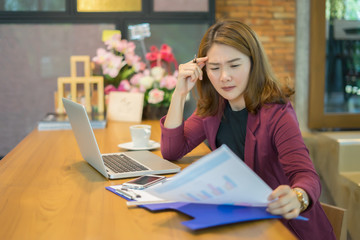 young Asian woman sitting at table in front of laptop, sleepy, tired, overworked, lazy to work....