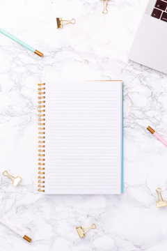 Festive golden stationary on white marble background. Feminine job, gender equality, home office and career concept. Copy space