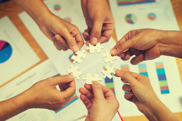 Hands of business people hold paper jigsaw puzzle and solving put pieces of the puzzle together. After Business group meeting to analyze and discuss the financial report,Investment Consultant solution