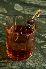 Artichoke Negroni cocktail on bar table. Tart, man's cocktail with Gin alcohol , Rosso, Cynar, close-up