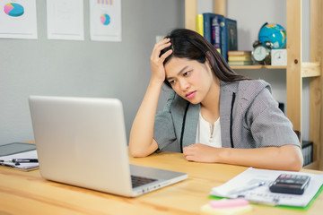 young Asian woman sitting at table in front of laptop, sleepy, tired, overworked, lazy to work. Attractive businesswoman yawning in home office relaxing or bored after work on laptop computer