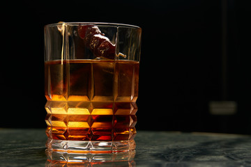 Artichoke Negroni cocktail on bar table. Tart, man's cocktail with Gin alcohol , Rosso, Cynar, close-up