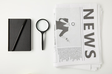 top view of notebook with pen, magnifying glass and newspapers isolated on grey